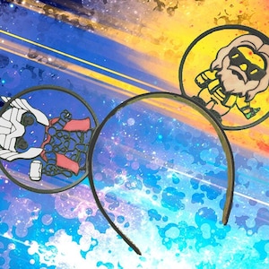 Pode incluir: Um par de orelhas de rato pretas com um fundo de galáxia colorido. A orelha esquerda apresenta uma imagem de desenho animado de Thor, enquanto a orelha direita apresenta uma imagem de desenho animado de um homem barbudo vestindo uma camisa amarela e óculos de sol.