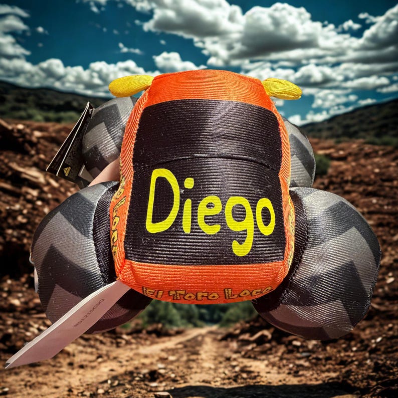 May include: Orange and black toy car with the name "Diego" in yellow lettering. The toy has gray wheels and yellow accents. The text "El Toro Loco" is also visible on the side of the toy.