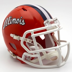 May include: A glossy red football helmet with white and navy blue stripes on top. The word "Illinois" is written in cursive on the side. The helmet has a white face mask and chin strap.