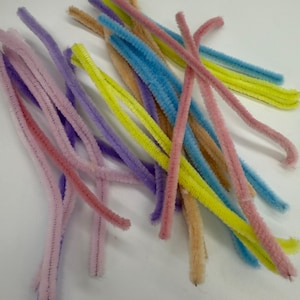 Könnte beinhalten: Ein Stapel bunter Pfeifenreiniger in Rosa, Lila, Gelb und Blau. Die Pfeifenreiniger sind weich und biegsam, was sie perfekt für Bastelarbeiten macht.