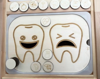 May include: A wooden educational toy with two teeth, one smiling and one frowning. The toy includes various food items, some good for teeth and some bad for teeth. The toy is designed to teach children about healthy eating habits.