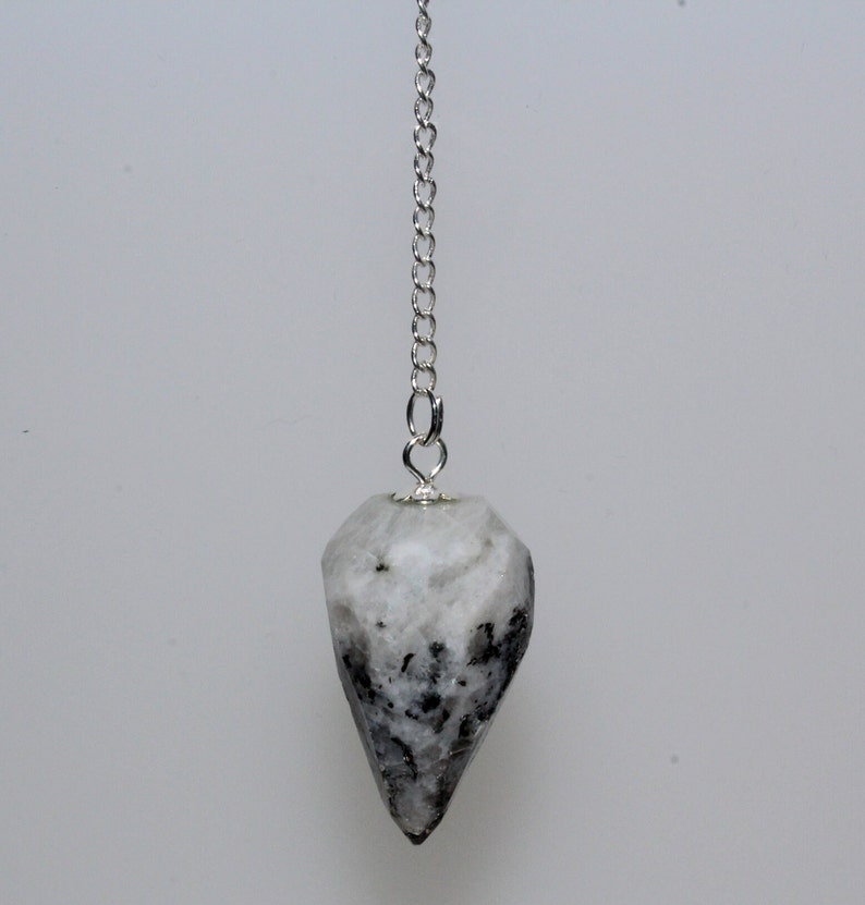 Puede incluir: Un p&eacute;ndulo de cristal blanco y negro con una cadena plateada.