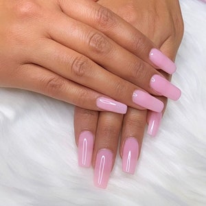 May include: Close-up of hands with long, light pink, coffin-shaped acrylic nails.