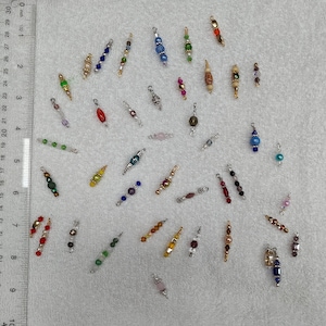 May include: Assortment of colorful beaded jewelry findings, including silver, gold, and copper tones. The beads are in various shapes and sizes, including round, square, and rectangular. Some beads have a metallic finish, while others have a matte finish.