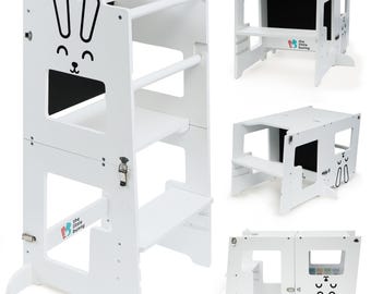 May include: White wooden learning tower with a bunny design. The tower has three shelves and a step stool. It can be converted into a table and chair set. The tower is designed for children to help them reach countertops and participate in activities with adults. The tower is made of high-quality wood and is safe for children.