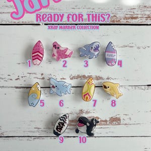 May include: A selection of ten vibrant, cartoon X-ray marker designs featuring surfboards, sharks, and an orca. The image includes the text "Jaw" and "Ready FOR THIS?" at the top, along with "XRAY MARKER COLLECTION". The designs are numbered 1 to 10.