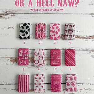 Op de afbeelding: Twaalf vierkante nagelstickers in roze en wit met verschillende ontwerpen, waaronder koe-print, sterren, hoefijzers en cowboyhoeden. De stickers zijn gerangschikt in vier rijen van drie. De tekst "IS HE A YEEH HAW? OR A HELL NAW?" staat bovenaan de afbeelding. De tekst "X-RAY MARKER COLLECTION" staat onder de tekst.