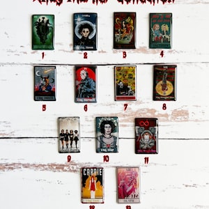 Könnte beinhalten: Ein Set mit 13 Tarotkarten zum Thema Horrorfilme. Jede Karte zeigt einen anderen Horrorfilmcharakter oder eine Szene. Die Karten sind auf einer weißen Holzoberfläche in einem Raster angeordnet. Die Karten sind mit dem entsprechenden Tarotkartennamen und der Nummer beschriftet.