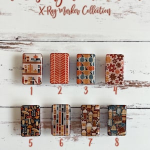 Könnte beinhalten: Acht verschiedene Herbst-Designs für X-Ray-Marker. Die Designs beinhalten Kürbisse, Blätter, Bücher, Kaffeetassen und Pilze. Die Marker sind von 1 bis 8 nummeriert.