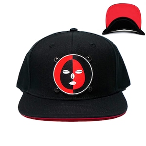 May include: Black and red baseball cap with a circular patch featuring a stylized face design. The cap has a red underside.