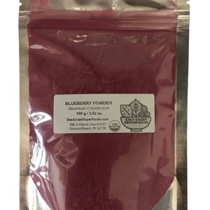 May include: A silver resealable pouch containing a red blueberry powder. The pouch has a label that reads "Blueberry Powder Vaccinium Corymbosum 100 g / 3.52 oz EastCoastSuperfoods.com 3865 S. Atlantic Ave. #1033 Ormond Beach, FL 32176 EAST COAST SUPERFOODS."