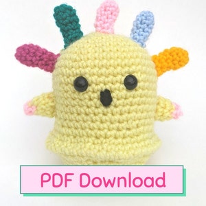 May include: A crocheted yellow amigurumi toy with colorful crocheted spikes and black eyes. The toy is shaped like a ghost and has a small black mouth. The text "PDF Download" is visible at the bottom of the image.