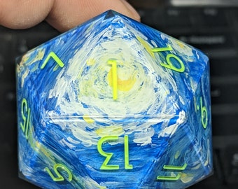 May include: A blue and yellow painted dice with green numbers. The dice has a swirling pattern reminiscent of a famous painting.
