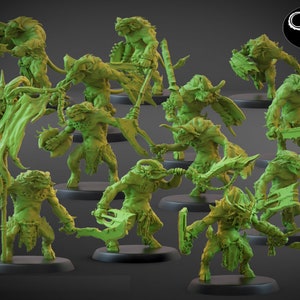 May include: A set of 12 green plastic miniature figures of horned, demonic creatures with various weapons and poses. The figures are standing on black bases.