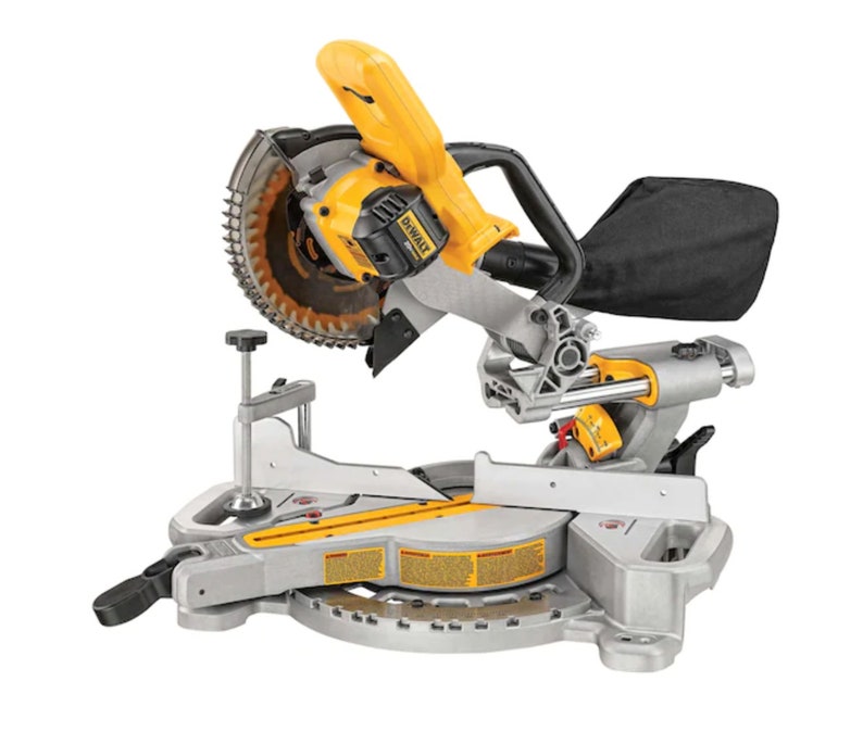 Puede incluir: Una sierra ingletadora amarilla y plateada con una hoja circular. La sierra tiene un mango negro y una bolsa para el polvo negra. La marca "DEWALT" es visible en la carcasa del motor. La sierra est&aacute; dise&ntilde;ada para cortar madera y otros materiales.
