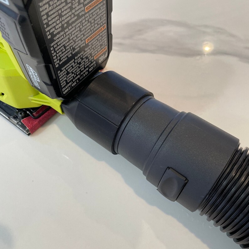 以下が含まれることがあります： 黒い掃除機ホースが、ライムグリーンと黒の電動サンダーに取り付けられています。サンダーには赤いサンディングパッドが付いています。黒いバッテリーがサンダーに取り付けられています。バッテリーには「LI-ION 18V 1.3Ah/24Wh」の文字があります。