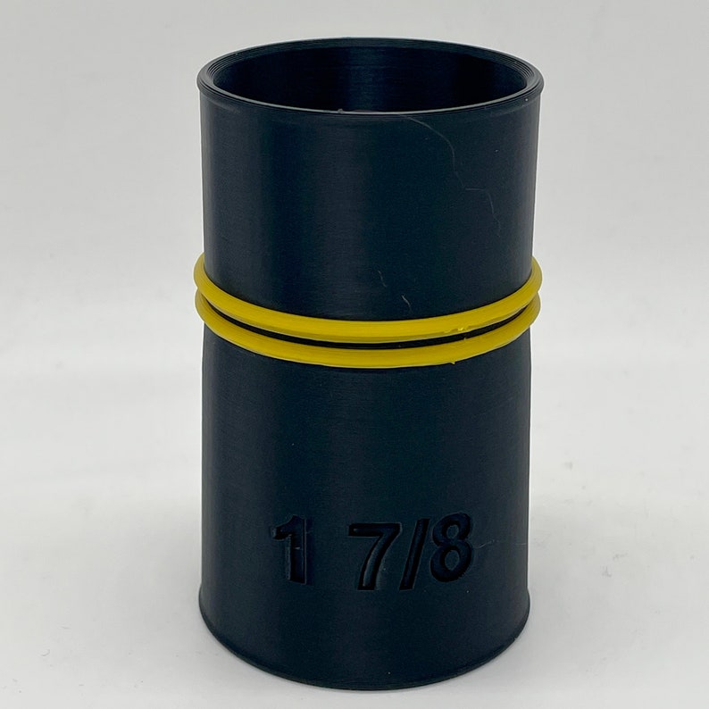 May include: A black cylindrical object with a yellow band around the middle. The object has the number "1 7/8" printed on the side. The object is likely a plumbing fitting or connector.