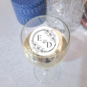 Peut inclure: Un autocollant rond blanc avec des motifs floraux noirs et les lettres E & D dans un cercle.