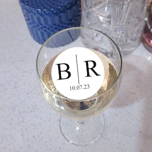 Peut inclure: Un verre de vin blanc avec un autocollant rond blanc qui dit "B|R 10.07.23".