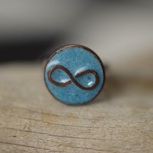 anillo azul hecho de esmalte con símbolo de infinito