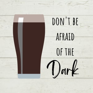 May include: A digital illustration of a pint glass filled with dark beer. The text "DON'T BE AFRAID OF THE Dark" is written in black script next to the glass. The background is a light wood grain pattern.