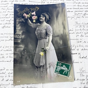 Década de 1900 - Postal con una joven, flores y la palabra "Heureuse fête"