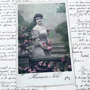 Década de 1910 - Postal con una joven, flores y la palabra "Heureuse fête"