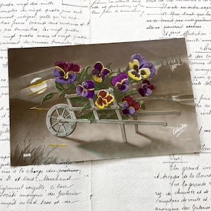 Década de 1910 - Cartão postal com um carrinho de mão cheio de flores