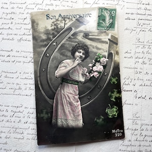 Década de 1910 - Postal con una joven, una herradura y la frase "Bonne anniversaire" (Feliz cumpleaños)