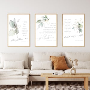 Könnte beinhalten: Drei gerahmte Kunstdrucke mit inspirierenden Zitaten und botanischen Illustrationen. Die Drucke zeigen elegante Kalligraphie und aquarellartige Grünpflanzen in Grün- und Goldtönen. Die Rahmen sind hellholzfarben.