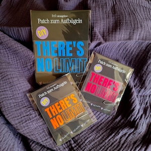 Könnte beinhalten: Drei Aufbügler mit dem Text "THERE'S NO LIMIT" in Blau, Orange und Pink. Die Aufbügler sind in Klarsichtfolie verpackt und liegen auf einem lila Stoffhintergrund. Der obere Aufbügler befindet sich in einer schwarzen Box.