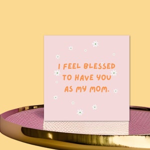 May include: Pink card with white flowers and the text "I feel blessed to have you as my mom."