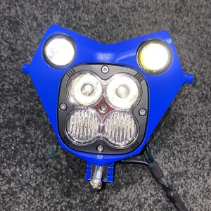 Puede incluir: Un conjunto de faros de motocicleta azules con dos luces laterales redondas y una matriz central de cuatro luces LED brillantes. El conjunto incluye hardware de montaje y cableado.