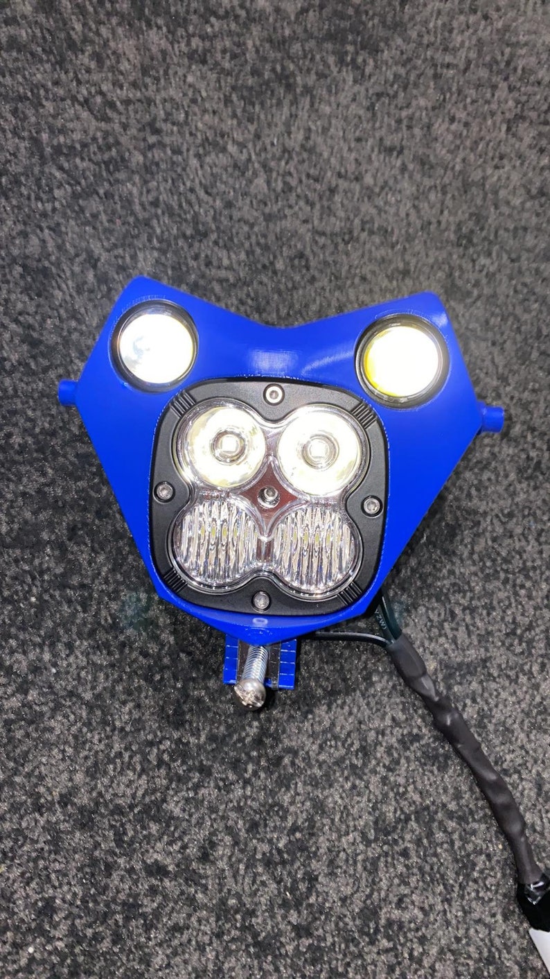 Puede incluir: Un conjunto de faros de motocicleta azules con dos luces laterales redondas y una matriz central de cuatro luces LED brillantes. El conjunto incluye hardware de montaje y cableado.