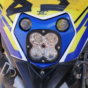 Puede incluir: Primer plano del carenado delantero de una motocicleta. El carenado es principalmente azul, amarillo y negro, con el n&uacute;mero "85" en un lugar destacado. Cuenta con m&uacute;ltiples luces LED y las letras "TNC".