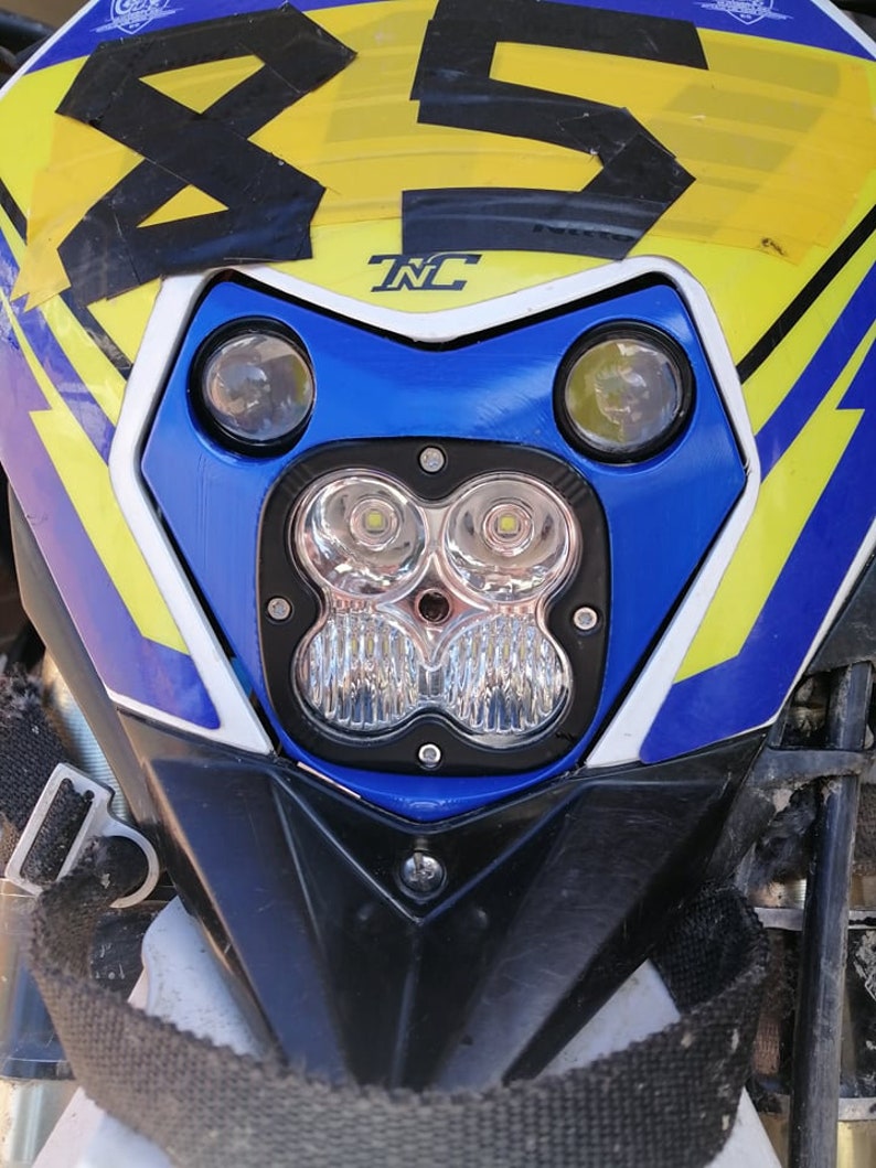 Puede incluir: Primer plano del carenado delantero de una motocicleta. El carenado es principalmente azul, amarillo y negro, con el n&uacute;mero "85" en un lugar destacado. Cuenta con m&uacute;ltiples luces LED y las letras "TNC".