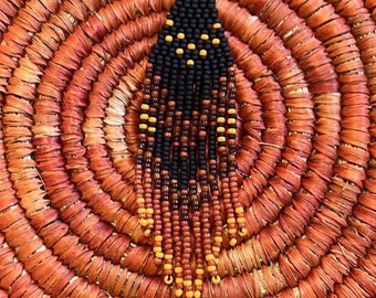 Könnte beinhalten: Ein Paar Perlenohrringe in Schwarz, Braun und Orange. Die Ohrringe sind tropfenförmig und haben einen silbernen Haken.