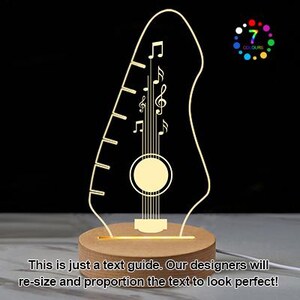 Pu&ograve; includere: Lampada a LED a forma di chitarra con note musicali e buca, su una base di legno. La lampada emette una luce gialla calda e presenta il testo "7 COLOURS". &Egrave; visibile anche il testo "This is just a text guide. Our designers will re-size and proportion the text to look perfect!"