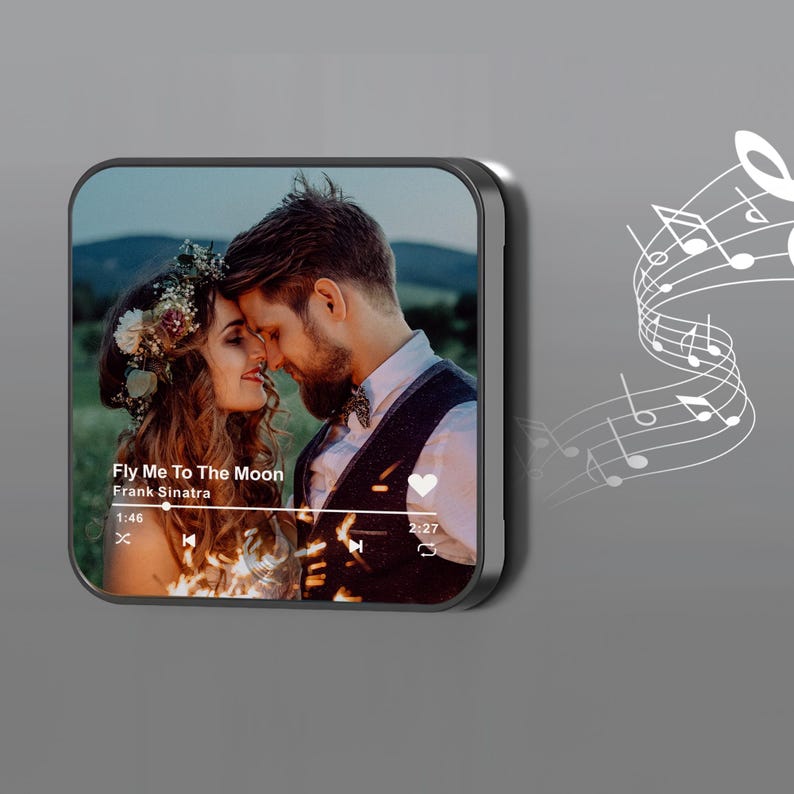 May include: A black and silver music player displays a romantic photo of a couple with the text "Fly Me To The Moon" by Frank Sinatra. Musical notes are on the right side of the player.