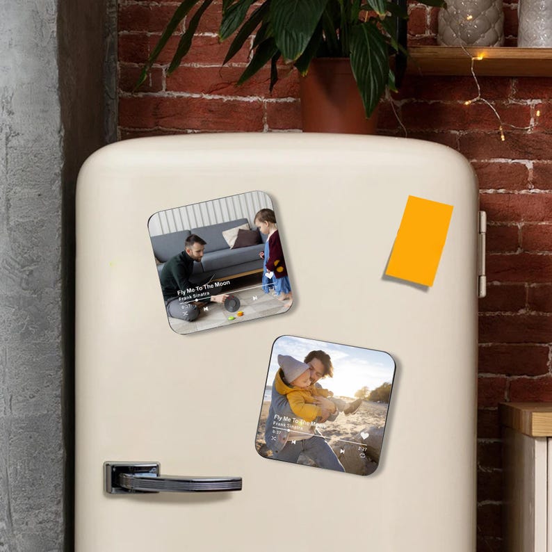 May include: Rectangular magnets with images of a father and child. One magnet shows a man and child listening to music, the other shows a man and child playing. The text "Fly Me To The Moon" is visible on the magnets.