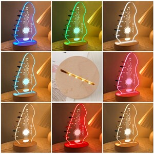 Pu&ograve; includere: Luce notturna a LED a forma di chitarra con la scritta "Music is life". La luce in acrilico &egrave; visualizzata in vari colori, tra cui blu, verde e rosso, e poggia su una base di legno. Il design presenta una paletta di chitarra.