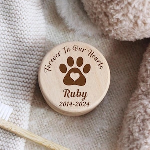 May include: A wooden keepsake box with a paw print and heart design. The box is engraved with the text "Forever In Our Hearts" and the name "Ruby" with the dates "2014-2024".