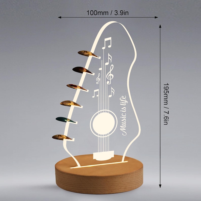 Pu&ograve; includere: Lampada a LED a forma di chitarra, alta 19,5 cm e larga 10 cm, con la scritta "Music is life". La lampada presenta una base in legno e un contorno di chitarra in acrilico trasparente con note musicali e sei plettri.
