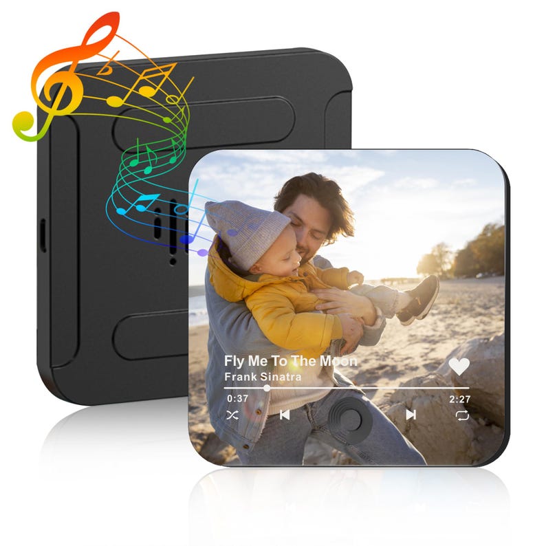 May include: Black square music player with a screen displaying a photo of a person holding a baby. The screen shows the song "Fly Me To The Moon" by Frank Sinatra. Colorful musical notes emanate from the player.