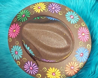 May include: A brown hat with a mesh crown and a wide brim. The brim is decorated with colorful painted flowers in shades of pink, yellow, blue, green, and purple.