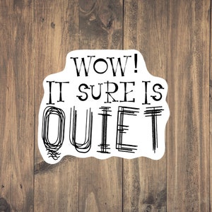 May include: White sticker with black text that reads "WOW! IT SURE IS QUIET" on a wood background.