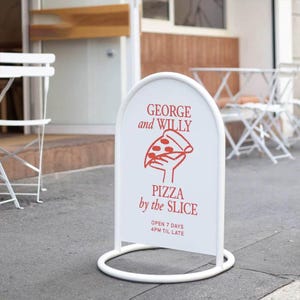 May include: A white, arched sidewalk sign with a red pizza slice graphic and the text "GEORGE and WILLY PIZZA by the SLICE." The sign also states "OPEN 7 DAYS 4PM TIL LATE." The sign is supported by a white, circular base.