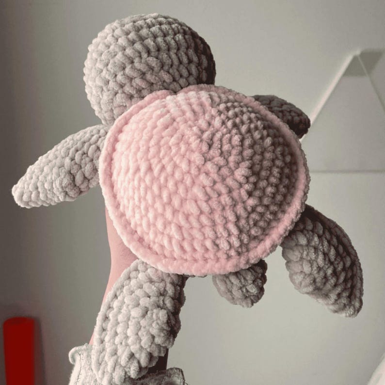 A turtle crochet plushie made with soft yarn, made with colours pink and grey. This is a medium sized turtle. This listing is a crochet pattern PDF tutorial.