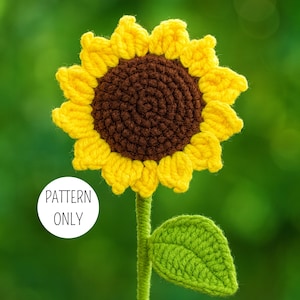 Peut inclure: Un tournesol au crochet fait à la main avec des pétales jaunes, un centre marron, une tige verte et une feuille verte. Le texte "PATTERN ONLY" est dans un cercle blanc. Le fond est vert flou.