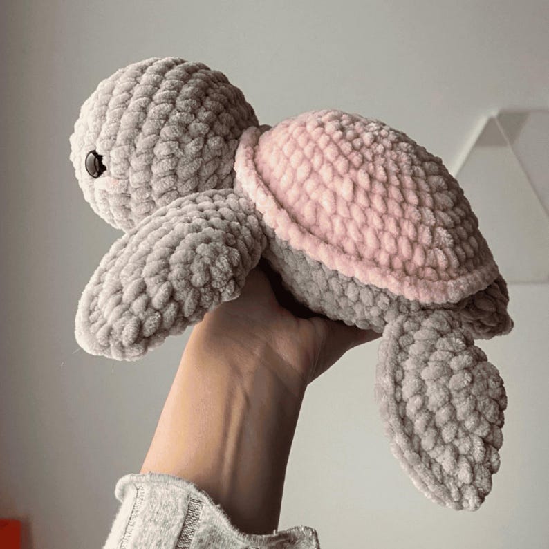A turtle crochet plushie made with soft yarn, made with colours pink and grey. This is a medium sized turtle. This listing is a crochet pattern PDF tutorial.